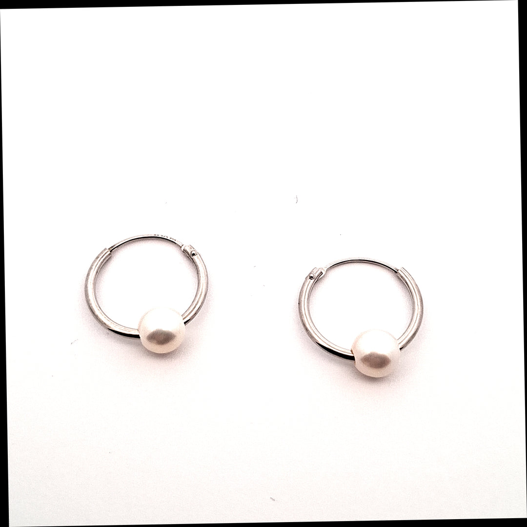 Pair of silver hoop earrings with a central pearl on a white background
