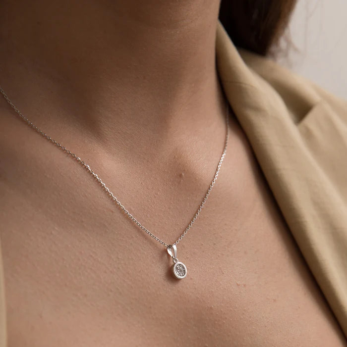 A close-up of a person wearing a delicate silver chain necklace