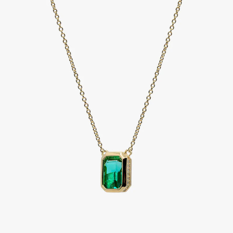 A gold chain necklace with a rectangular green gemstone pendant, shown against a plain light gray background.