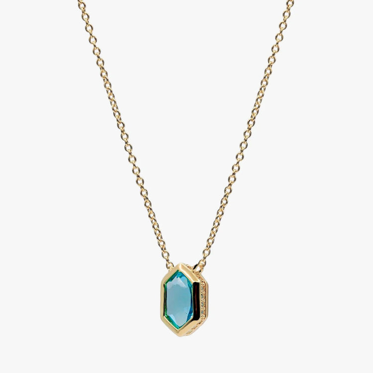 A gold chain necklace with a hexagonal pendant featuring a faceted light blue-green gemstone and a gold bezel setting, shown against a plain light gray background.