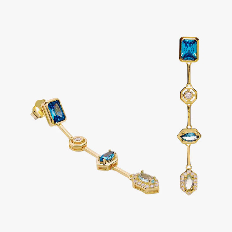 A pair of gold-plated dangle earrings featuring rectangular and marquise-cut blue gemstones, accented with small clear crystals, shown on a light gray background.