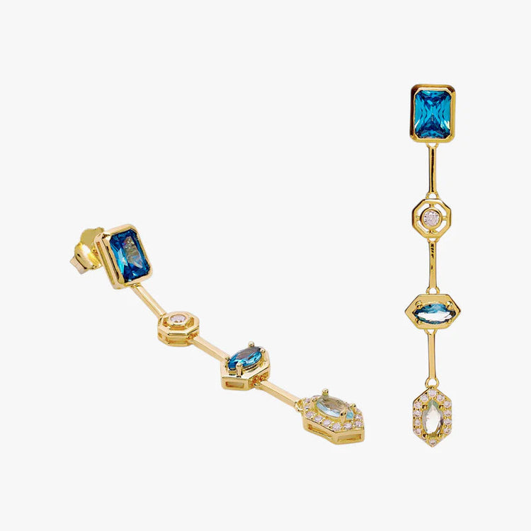 A pair of gold-plated dangle earrings featuring rectangular and marquise-cut blue gemstones, accented with small clear crystals, shown on a light gray background.