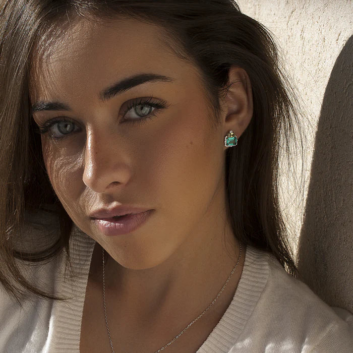 A close-up lifestyle shot of a woman wearing a matching jewelry set featuring a silver necklace with a square-cut green gemstone pendant and a matching ring on her finger.