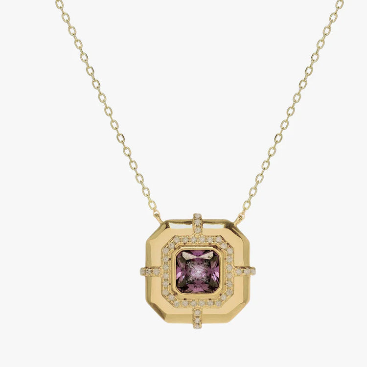 A gold pendant necklace featuring a square, geometric gold frame with a central cushion-cut purple gemstone and a halo of small clear stones, suspended from a delicate gold chain against a light gray background.