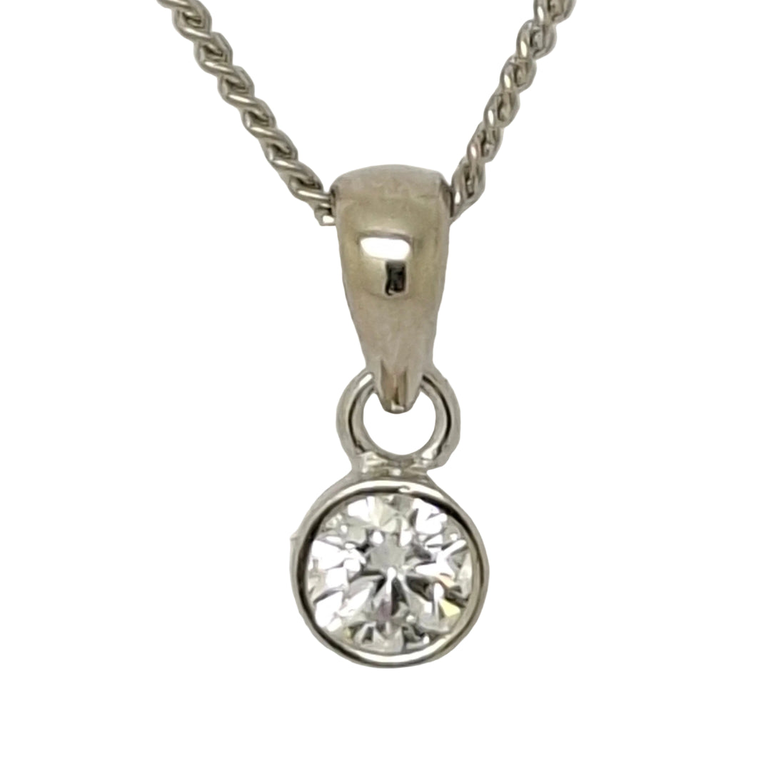 Close-up of a silver necklace with a diamond pendant on a light gray background