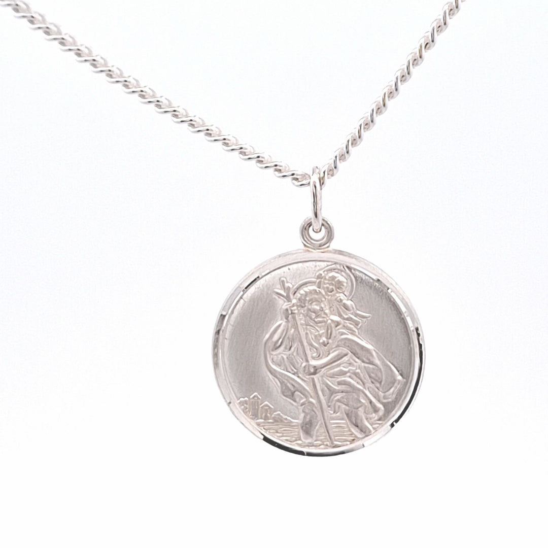 Silver pendant necklace with a religious design on a white background