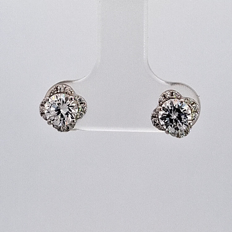 Pair of diamond earrings on a clear stand against a light gray background