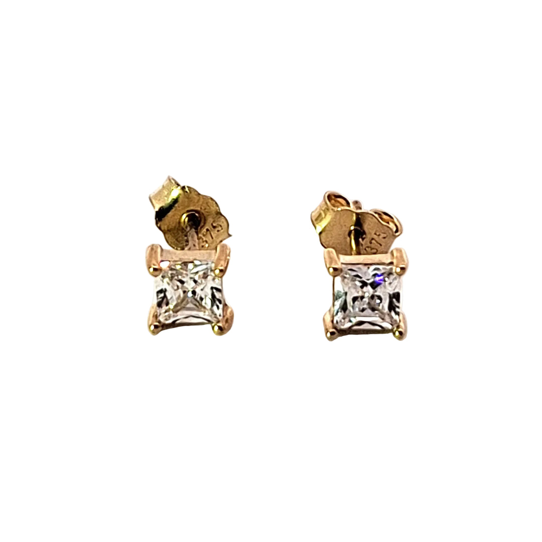Pair of gold earrings with clear gemstones on a white background
