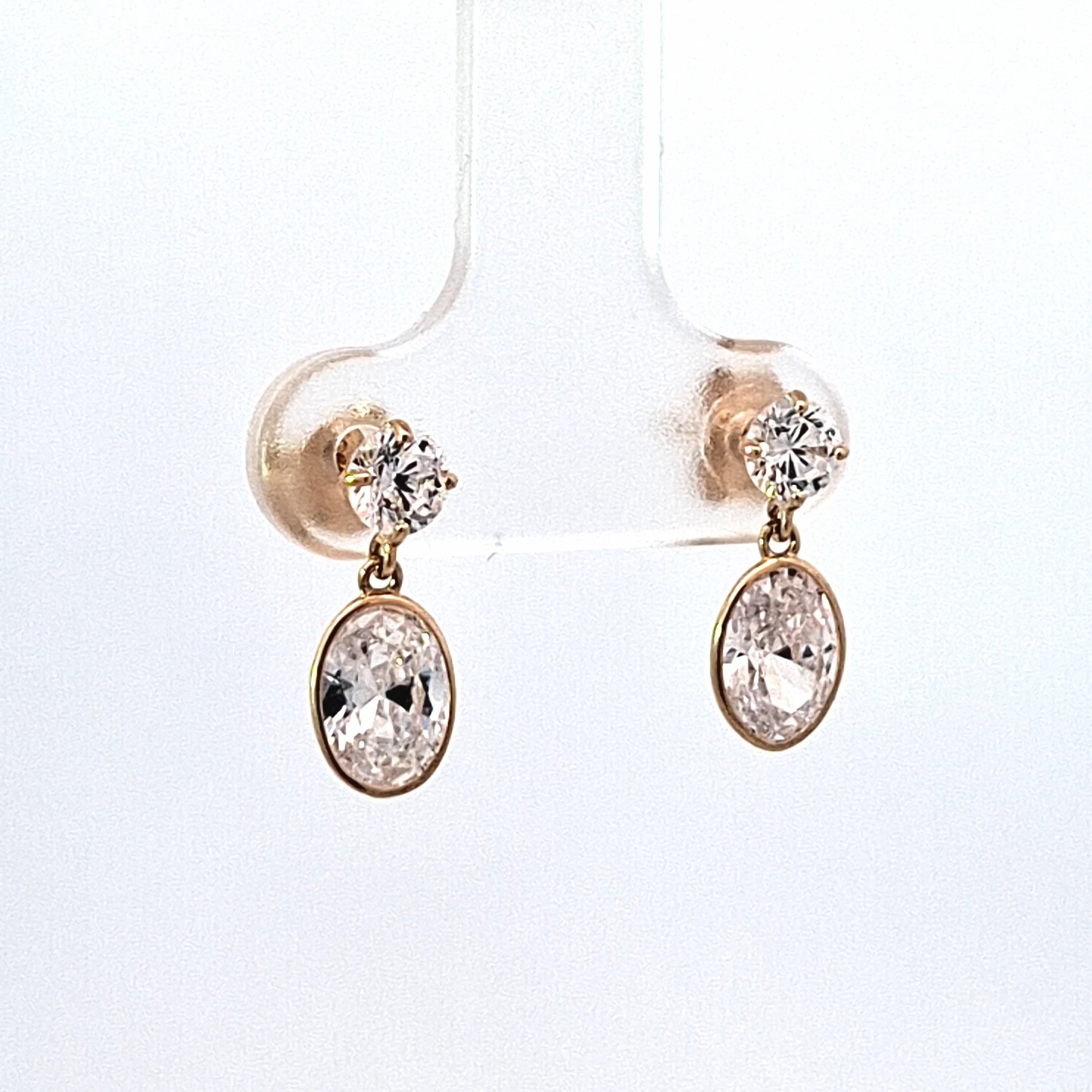 Gold earrings with clear gemstones on a white background