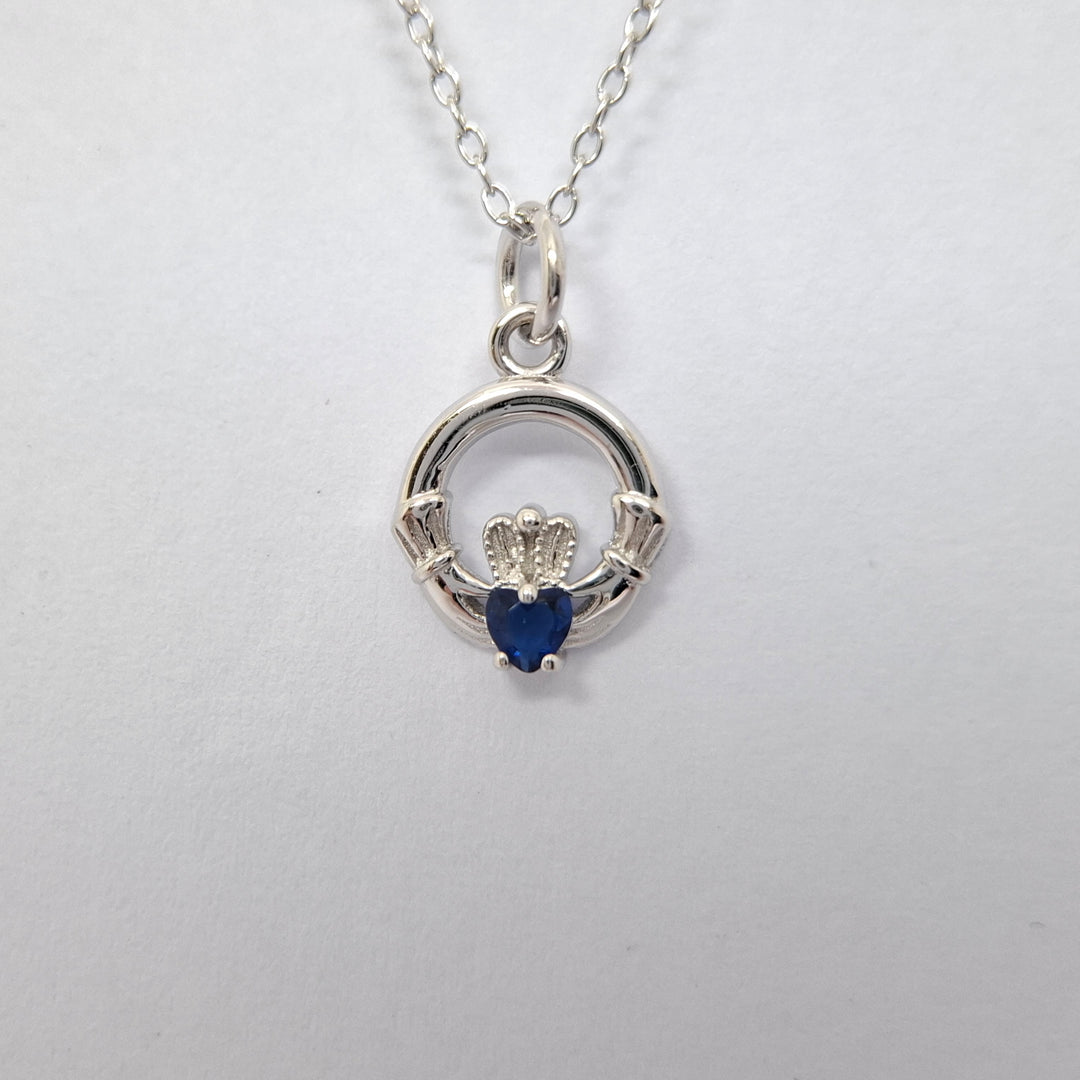 Silver Claddagh pendant with a blue heart stone on a white background