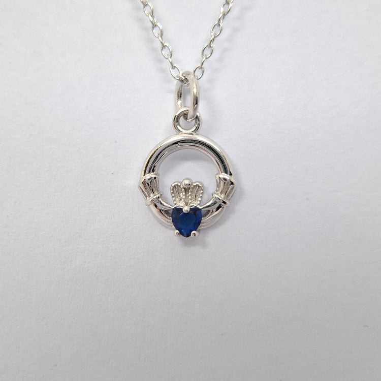 Silver Claddagh pendant with a blue heart stone on a white background