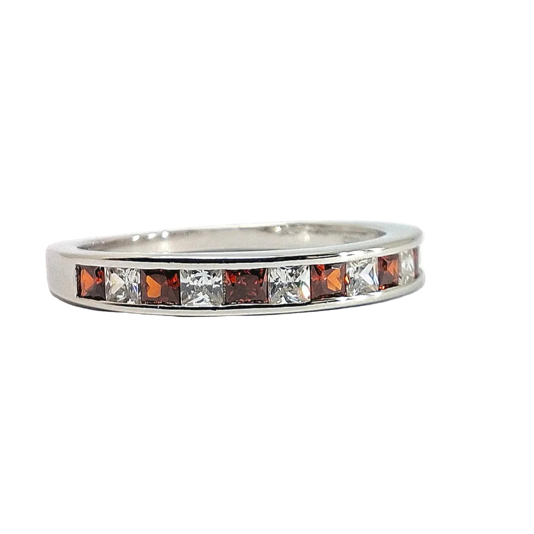 A silver band ring featuring a row of alternating clear and orange-brown square gemstones, photographed on a plain light background.