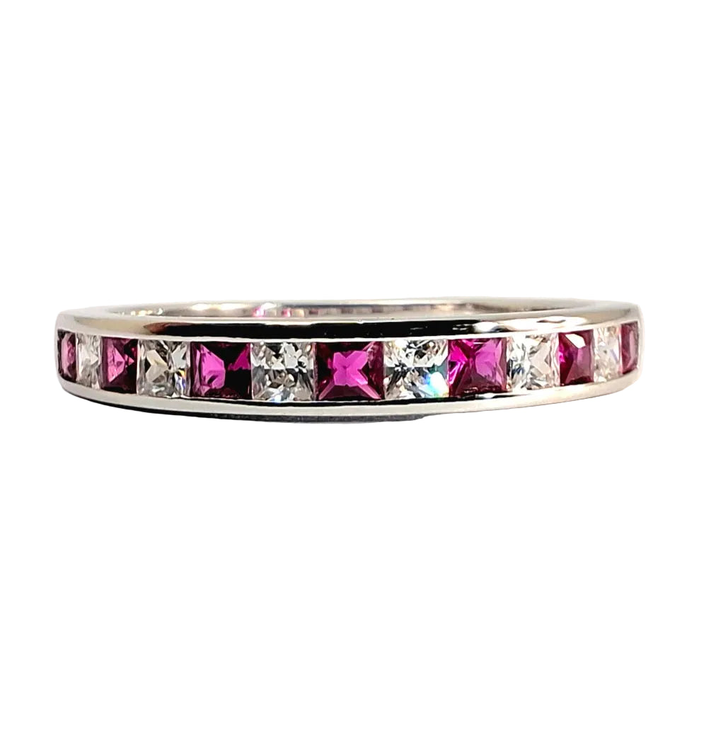 A silver band ring featuring a row of alternating pink and clear square-cut stones, photographed on a plain light background.