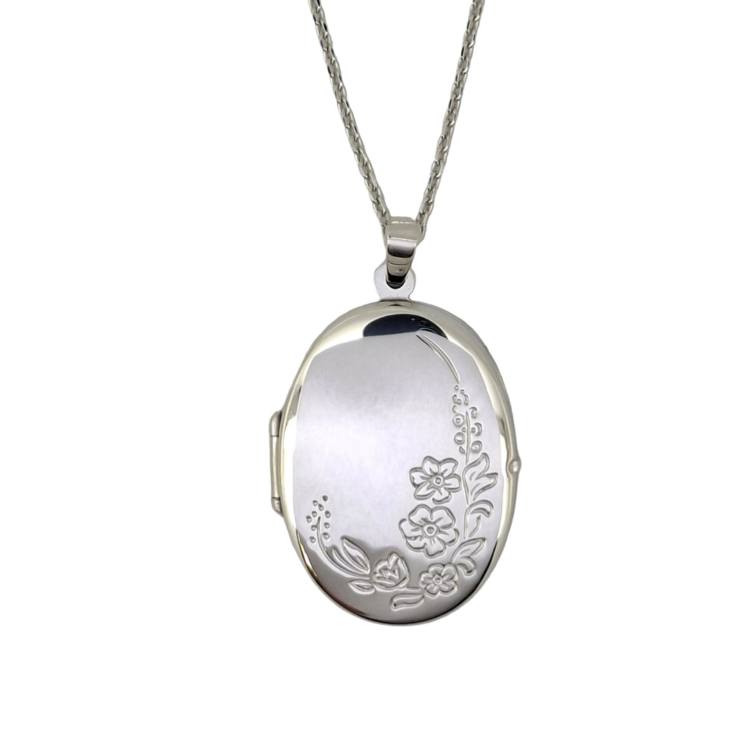 Silver locket with floral engraving on a gray background